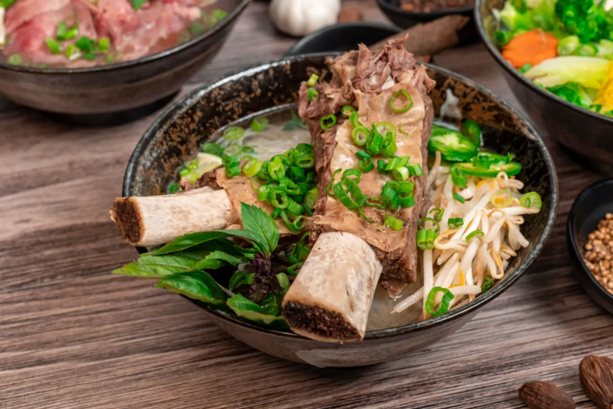 A bowl of SUP Noodle Bar pho topped with bone-in beef ribs, scallions, Thai basil and bean sprouts